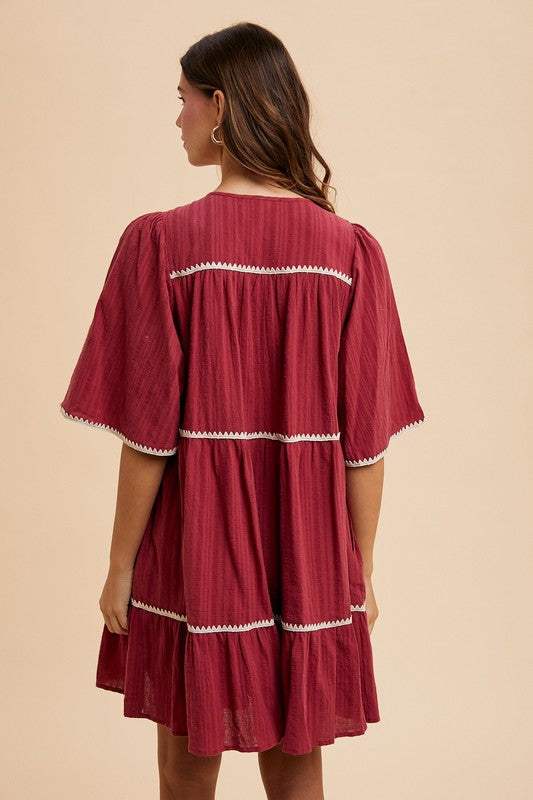 Burgandy Tassel DressEffortless charm in every detail. This breezy tiered dress features delicate contrast trim and a tassel-tie neckline for a touch of boho romance. The rich garnet hueMidi DressesBurgandy Tassel Dress